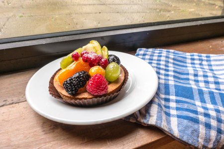 fresh fruit pie tart with kiwi, blueberry, orange and strawberry  in plate close to cotton kitchen towelsの写真素材