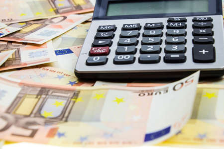 stack of 50 Euro money and calculatorの写真素材
