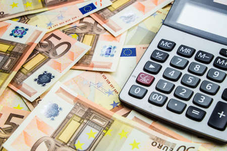 stack of 50 Euro money and calculatorの写真素材