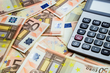 stack of 50 Euro money and calculatorの写真素材