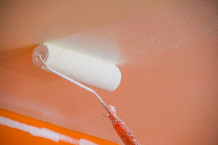 Painting the wall with paint roller.