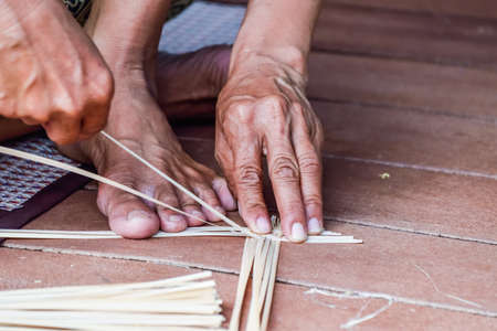 close up old woman's hands making a wicker basket.の写真素材