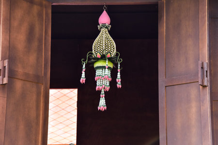 Thai handcraft from banana leaf and flowers haning in the middle of Thai wooden house window.の写真素材
