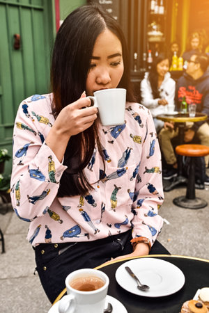 Long hair Asain girl drink coffee at coffee shop in Paris