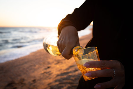 A girl pours wine at sunset on the sea