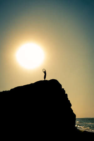 the girl stands on a rock in the backlightの写真素材