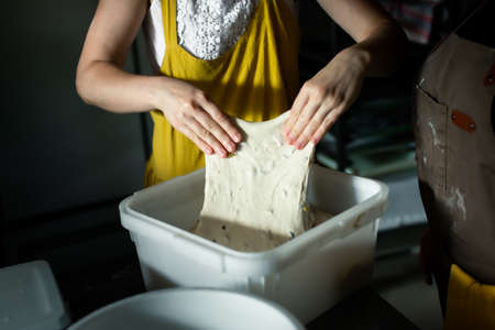 Folding the dough in a container in a bakeryの写真素材
