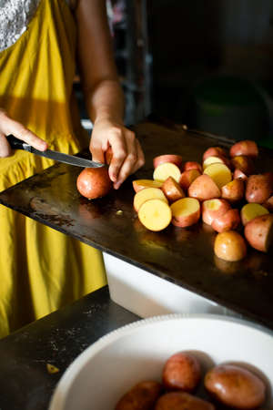 Cutting potatoes on a baking counter by a womanの写真素材