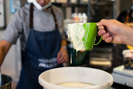 Baker measures sourdough for bread with a mugの写真素材