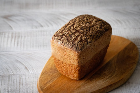 Rye artisan bread on a wooden board on a white backgroundの写真素材