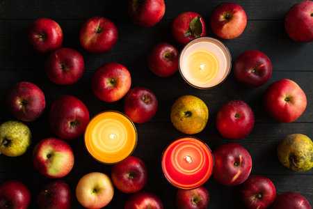 Imperfect red apples and yellow pears on a wooden dark background with candles. Bulk. Top view....