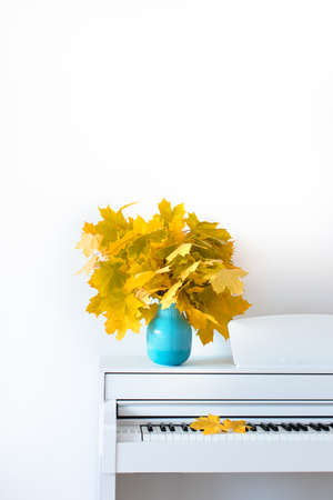 Maple leaves on the piano in a blue vase. The concept of autumn. Front view. Russia. Chekhov.の写真素材