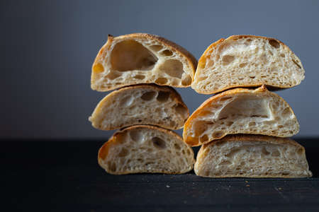 Artisan traditional bread. Italian ciabatta. Cut into halves and shot on a dark background. Homemade bread.の写真素材