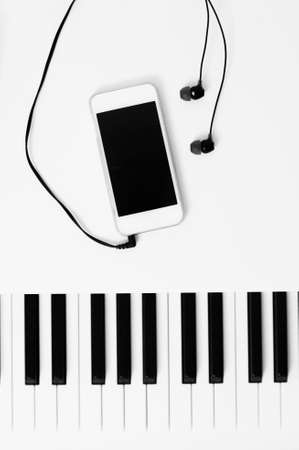 Piano keys and music playback device with headphones. Black and white photo. The concept of different technologies and approaches in music.の写真素材