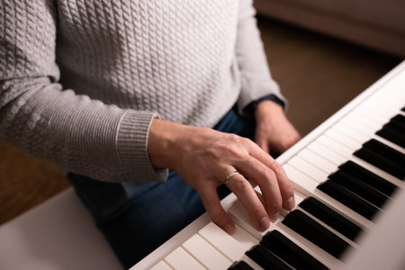Learning to play the piano. A man plays an instrument. Piano keys, pressed, side view.
