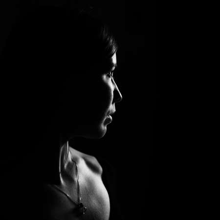 Portrait of a young woman in profile with dramatic light. Black and white photo.の写真素材