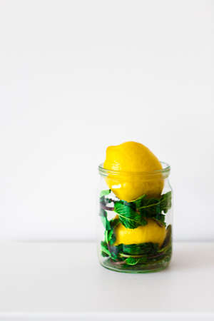 Yellow lemon and green mint in a transparent jar on a white background, Front view. Copy space.の写真素材