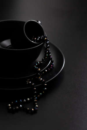 Black dishes on a black background with beads. Abstract photo. Side view.の写真素材