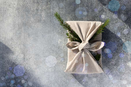Furoshiki style gift for Christmas or New Year on a gray background with bokeh. Flat lay. Copy space.の写真素材