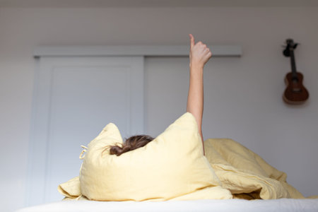 The girl sleeps in bed and raises her thumbs up. The concept of waiting for summer.の写真素材