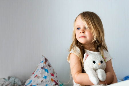 Portrait of a little girl in the childrens room hugging a toy. Smiling in the background of the room.の写真素材