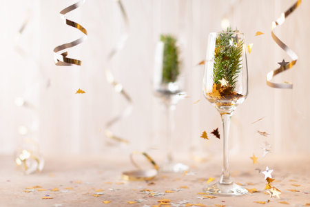 New Years champagne glasses with sparkles inside and a spruce tree. On a white background of tinsel and ribbons. Front view.の写真素材