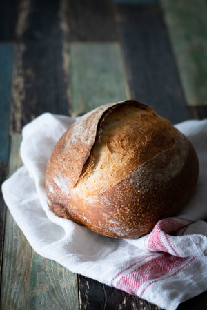 Homemade wheat whole grain sourdough bread on a dark background and a wooden table. Photo in front.
