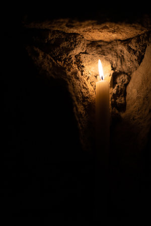 A candle burns against the background of masonry in the dark. Front view.の写真素材