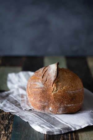 Homemade wheat whole grain sourdough bread on a dark background and a wooden table. Photo in front.の写真素材