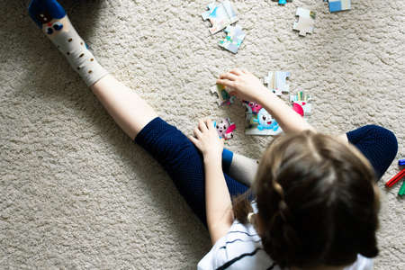 A girl plays in her room, collects a jigsaw puzzle. View from above.の写真素材