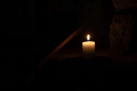 A candle burns against the background of masonry in the dark. Front view.の写真素材