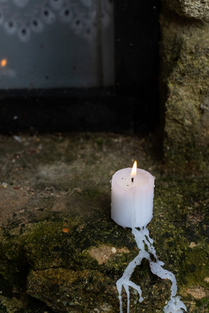 A candle burns on the windowsill of an old limestone house by the window. Front view.の写真素材
