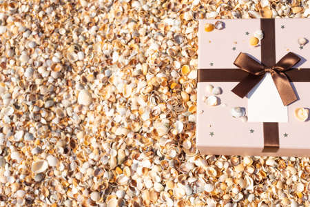 A box with a gift tied with a ribbon lies on the beach near the sea. Front view, vertical.の写真素材