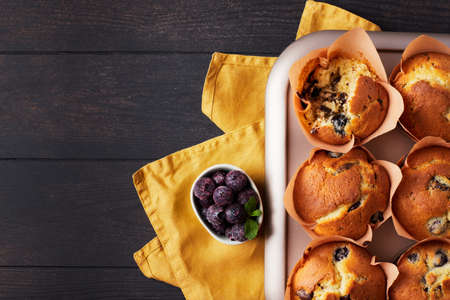 A group of mafins with berries and chocolate on a dark wooden background. FLat lay. Top view.の写真素材