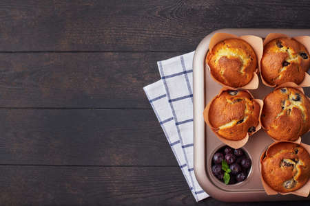 A group of mafins with berries and chocolate on a dark wooden background. FLat lay. Top view.の写真素材