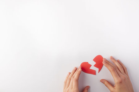 Broken heart and hands on a white background. Top view. Copy space. Place for text.