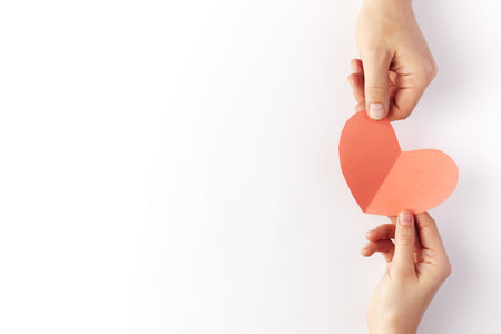 Valentines Day, red heart made of paper are held in the hands of a couple in love. Top view. Copy...