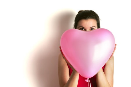 A woman holds an inflatable balloon in the shape of a pink heart. Birthday and valentines day...