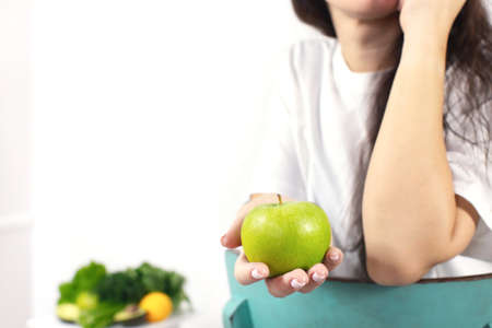 Close-up of a womans hand holding an apple. The concept of spring and vitamins. Detox food. Front view.の写真素材