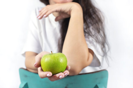 Close-up of a womans hand holding an apple. The concept of spring and vitamins. Detox food. Front...