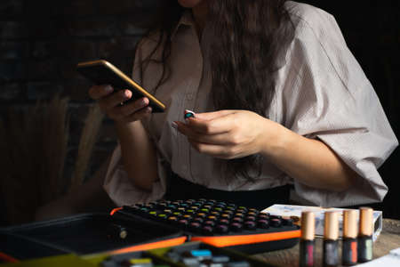 Concept of business and aromatic oils. A woman with a phone and a set of sample vials. Front view.の写真素材