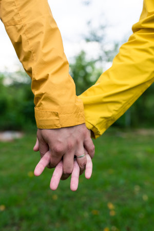 A married couple in yellow raincoats hold hands. Close-up. Front view.の写真素材