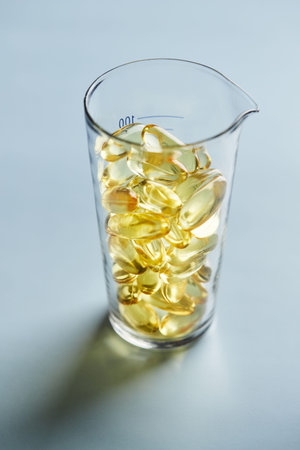 Capsules of omega-3 fatty acids on a blue background in a glass. The concept of medicine and a...
