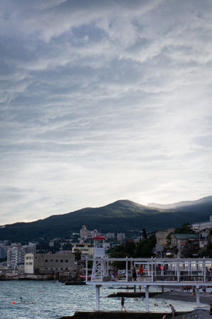 Mountain seascape. Sunset on the shore of a big city. The concept of vacation and relaxation. Vertical photo.の写真素材