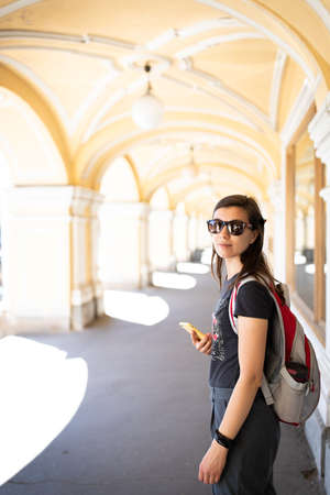 A tourist woman walks around the city with a smartphone. Front view.の写真素材