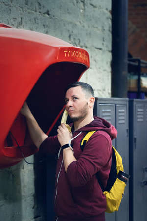 Portrait of a man calling a pay phone in a loft space. Translation: pay phone. Vertical photo.の写真素材