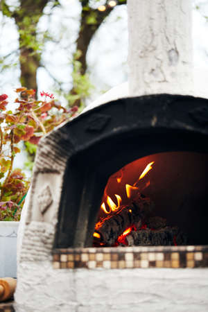Wood-fired pizza oven with birch logs for kindling. The fire burns and the oven heats up. Vertical photo.の写真素材