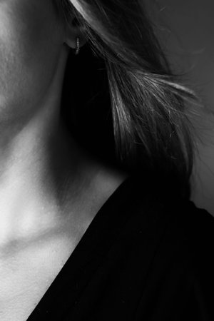 Young tender well-groomed womans neck in a photo in black and white. Vertical photo.