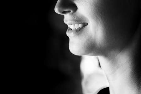 BW photo of an attractive woman. A large portrait on a dark background. Macro photo, bottom part of the face. Front view.の写真素材