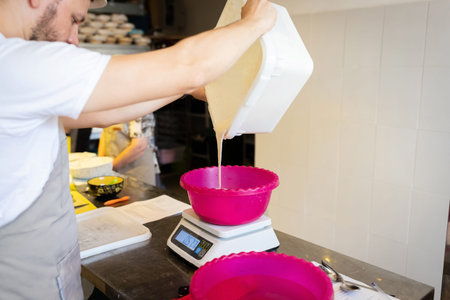 The process of making wheat bread. The baker adds liquid sourdough to the kneading container. Front...